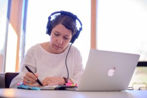 Professor wearing headphones and working at her laptop