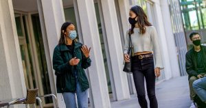 Two UBC students walking and talking outdoors, wearing masks during the COVID-19 pandemic.