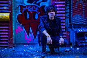 Image of Dr. Chris Patterson crouched in front of a wall of graffiti