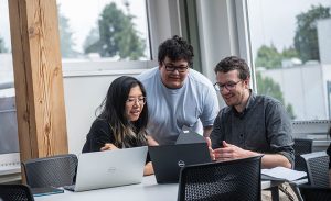 Three students working together looking at laptops