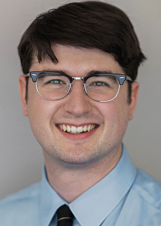 A headshot of Matthew Richardson. He is wearing a button-up light blue shirt with a tie and eyeglasses.