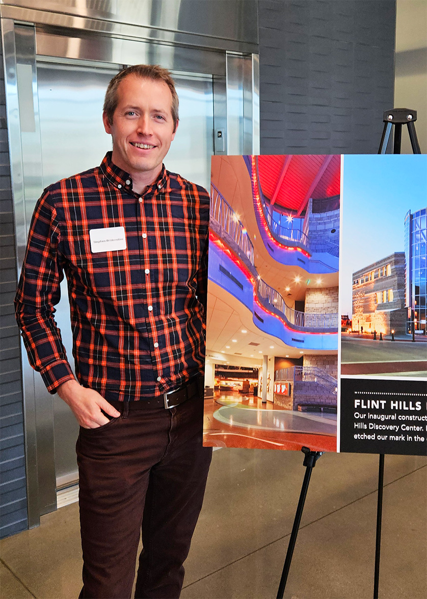 Stephen Bridenstine standing next to a Flint Hills Discovery Center display board