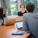 Three students having a discussion at a study room table.
