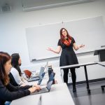 An instructor teaching a class in front of a whiteboard.